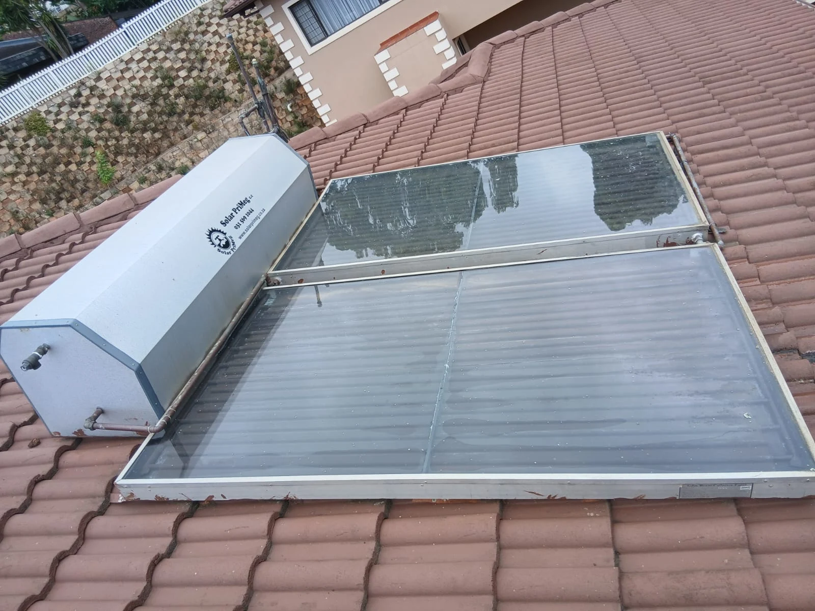 A solar geyser with flat collector panels installed on a tiled roof